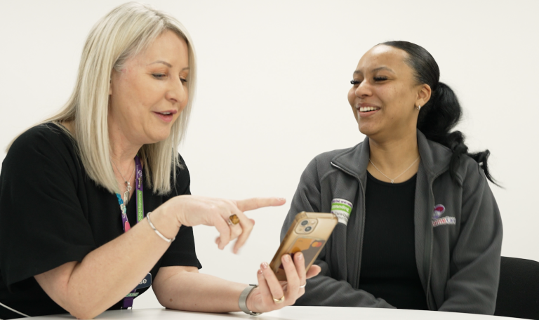 This is a picture of two women sitting at a table looking at a mobile phone