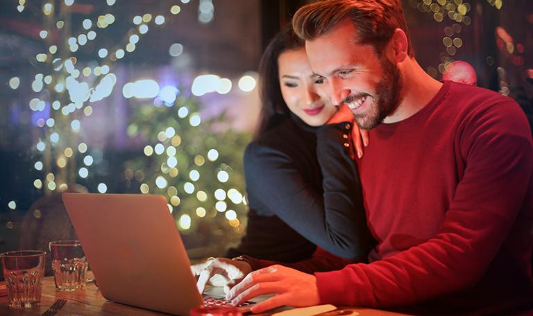 A couple looking at a laptop at Christmas time