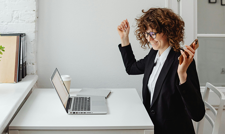 A woman celebrating on her laptop