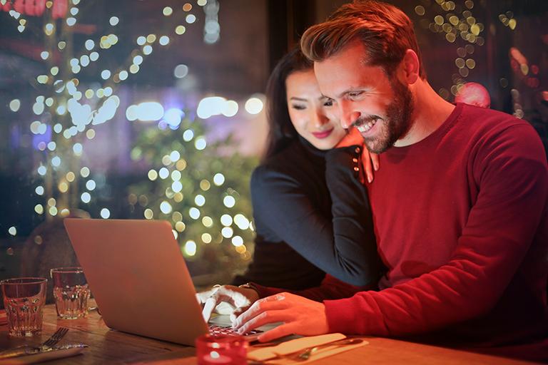 A couple looking at a laptop at Christmas time